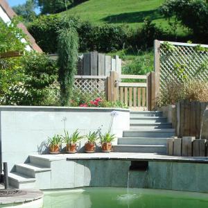 Escaliers de jardin composés de 3 paliers. Escaliers en pierre naturelle contournant la piscine naturelle. 