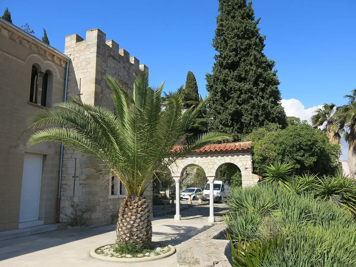Steinfassade, Palme, Zypresse und Gartenarkade am Castel Sainte-Claire in Hyères